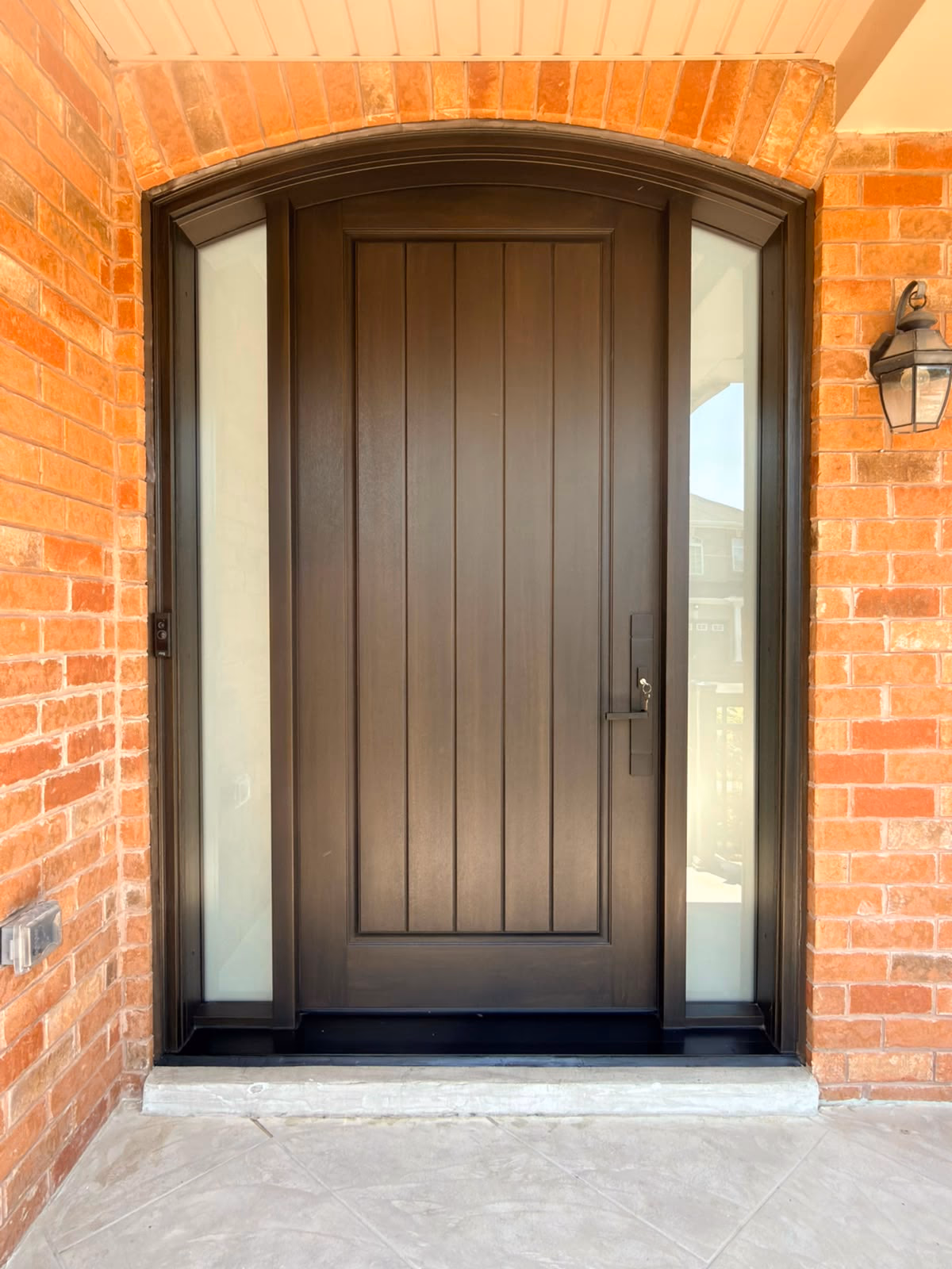 Tall dark wood entry door with narrow glass sidelights
